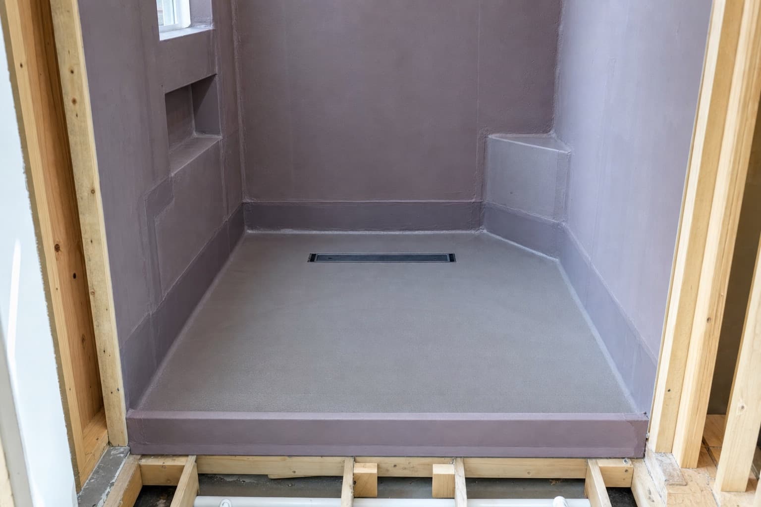 Shower waterproofing before tiling: a bonded membrane lapped up the walls over a sloped bed